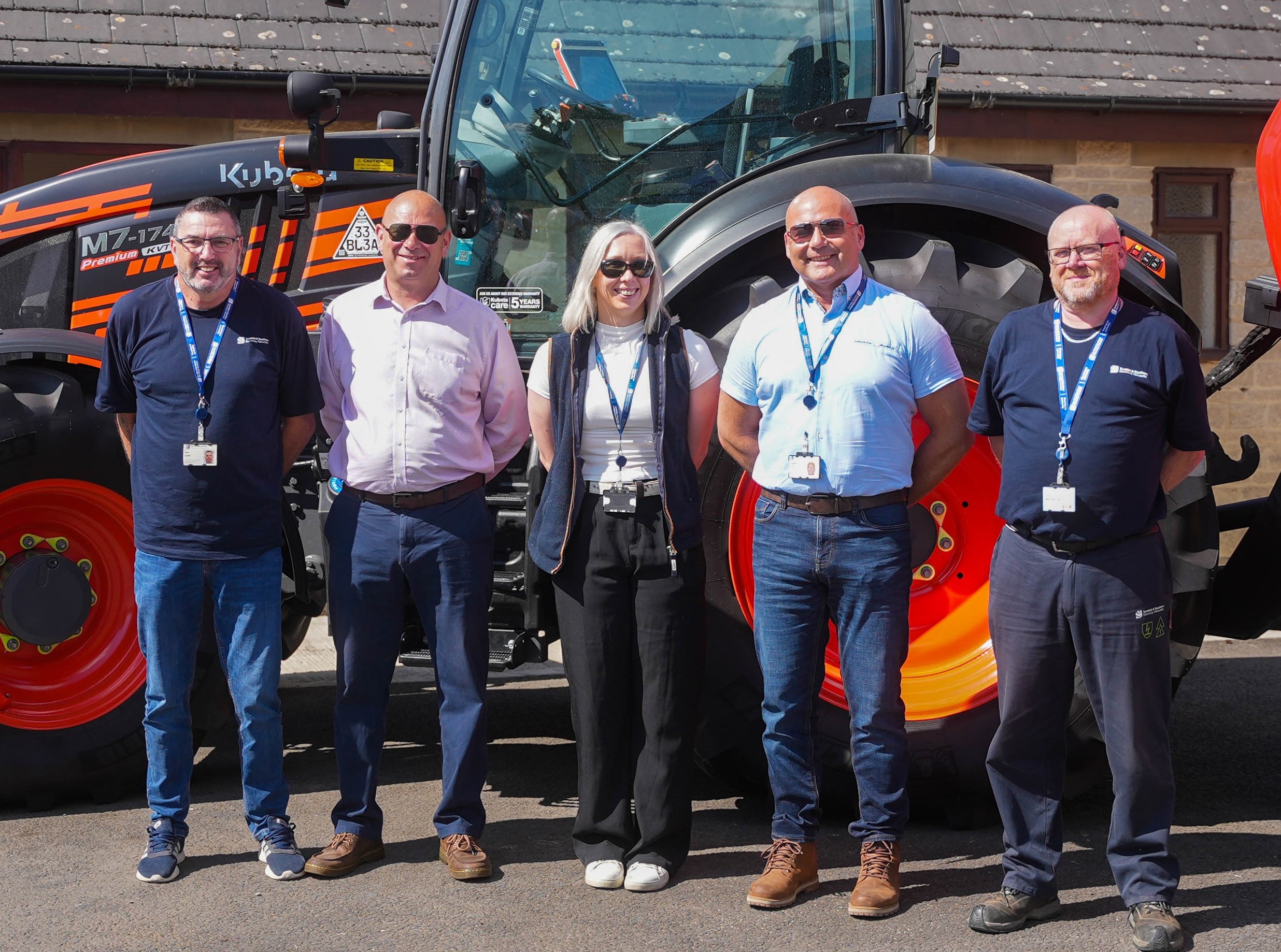 Safety team - four men and one woman standing in yard in front of red tractor