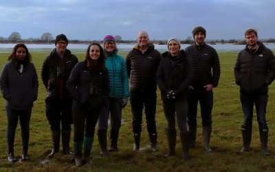 Group of people in a field, smiling and facing the camera 